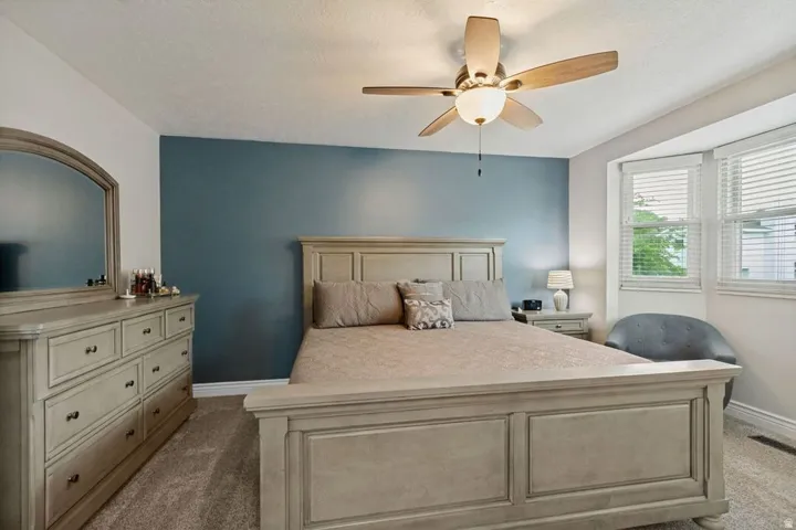 Recessed bay window, ceiling fan with integrated lighting, broad baseboards, and wall-to-wall carpeting