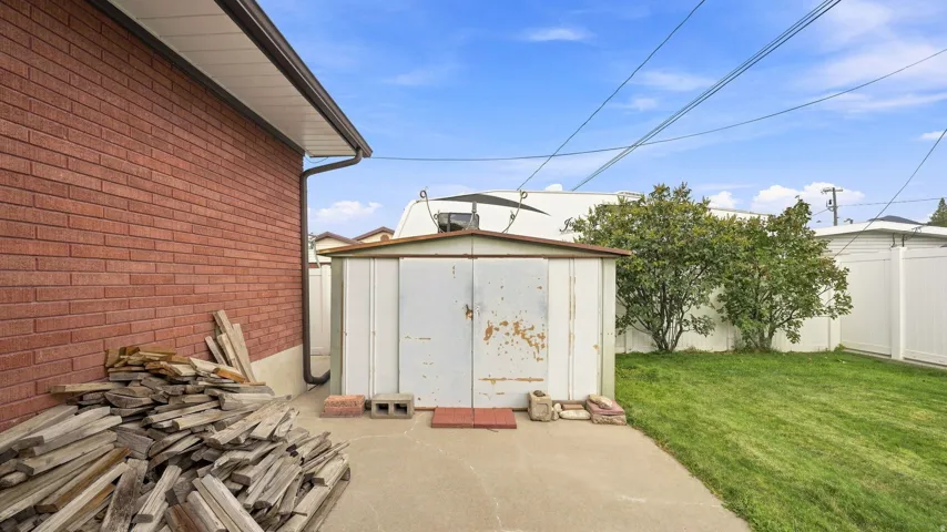Spacious backyard featuring mature landscaping, lush lawn, and a detached storage shed with pitched roof design