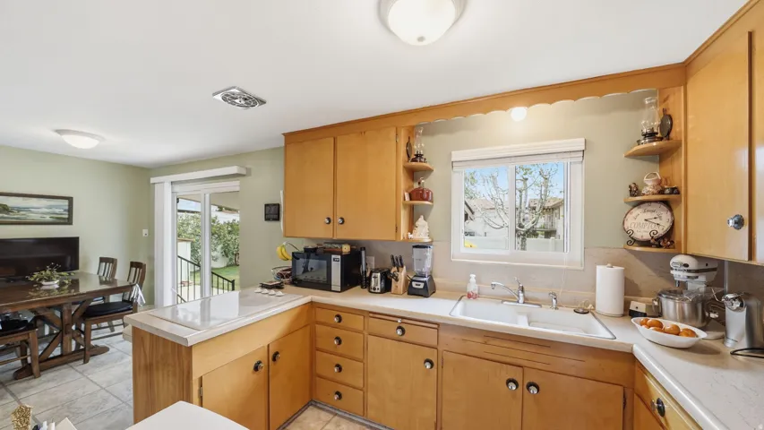 Kitchen featuring wood cabinetry, a double basin sink, and tile countertops