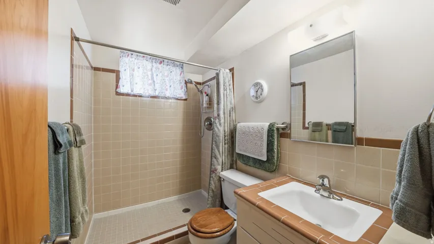 Bathroom with walk-in shower with tile surround.