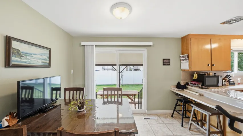 Kitchen and dining area featuring wood cabinetry, a breakfast bar, and a glass sliding door leading to the backyard