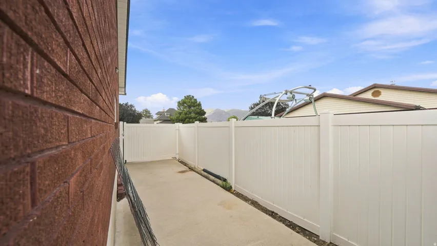 Spacious side yard featuring composite fencing with clean lines, concrete paving, and mature landscaping