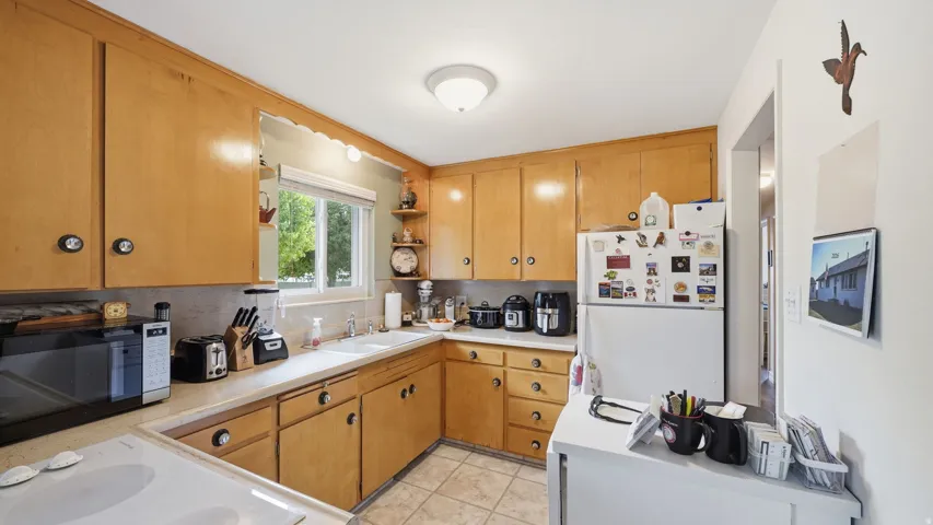 Kitchen with wood-finish cabinetry, white countertops, and a double basin sink