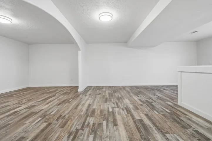 Spacious room featuring wood-finish flooring and recessed lighting