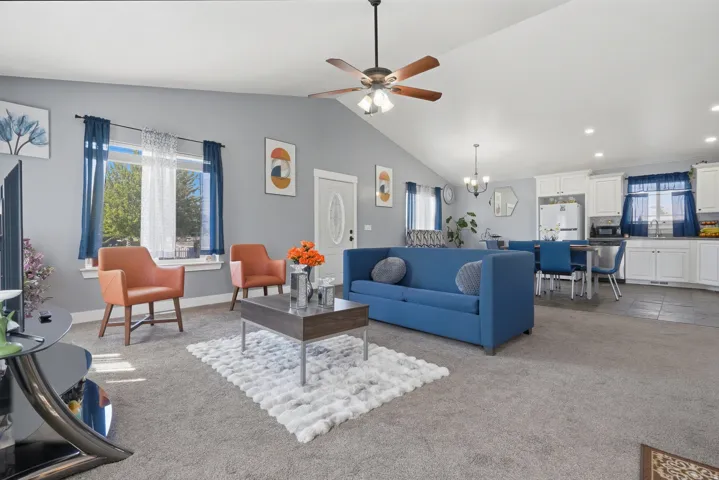 Vaulted ceiling with a ceiling fan, light gray wall paint, and gray carpet flooring