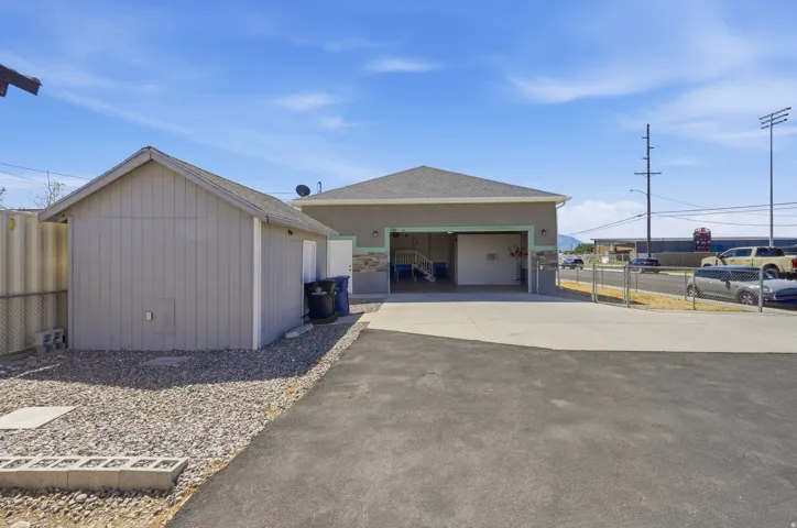 Detached shed with pitched roof, gravel landscaping, asphalt driveway, and concrete patio