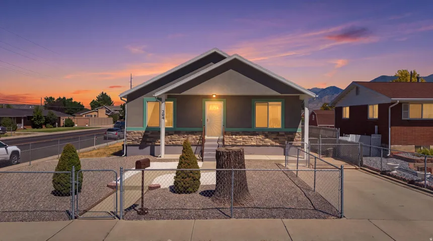 Single-story residence featuring a covered front porch, stone veneer and stucco exterior, and a gravel front yard