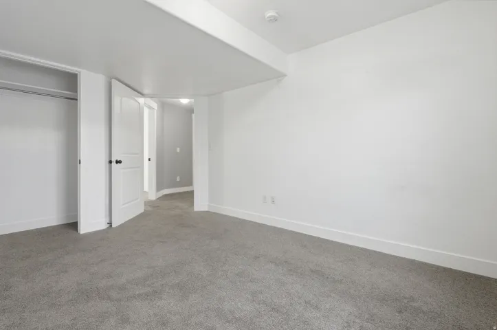Neutral tone walls, grey carpeting, white trim, white interior doors with black hardware, and an open closet