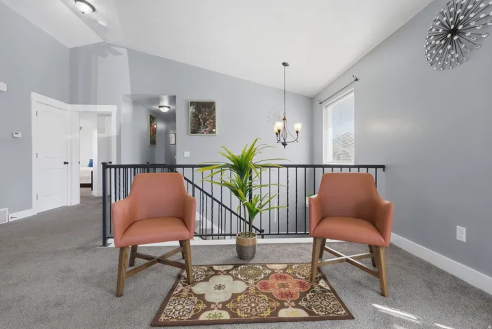 Spacious loft area with vaulted ceilings, gray carpeting, and black metal railings