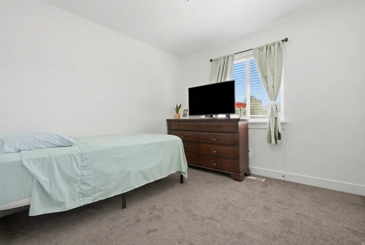 Window with horizontal blinds and drapes, carpeted flooring, and white walls