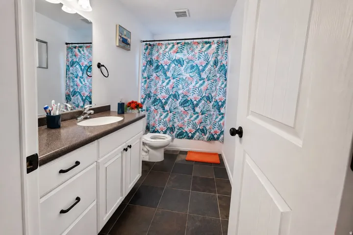 White vanity with ample storage, dark countertop, and integrated sink