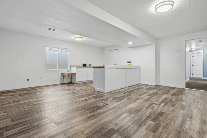 Wood-finish flooring, recessed lighting, white cabinetry, integrated sink, and an interior window
