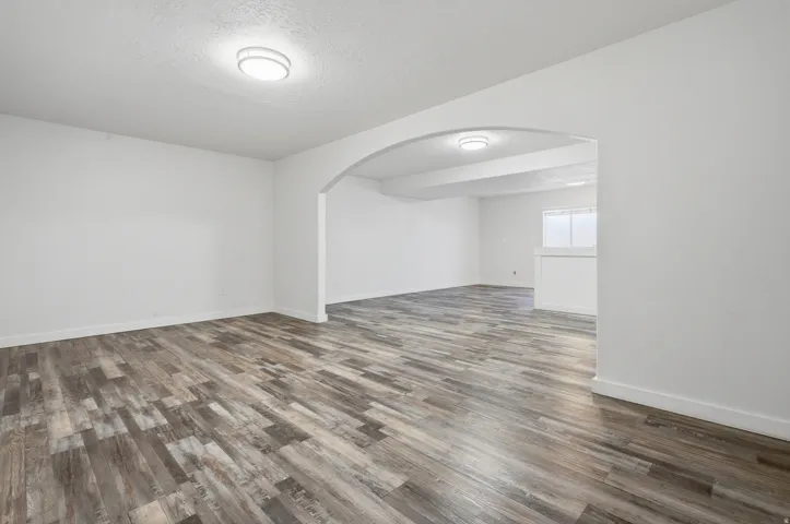 Archway entrance to additional living space, wood-finish flooring, and recessed ceiling lighting
