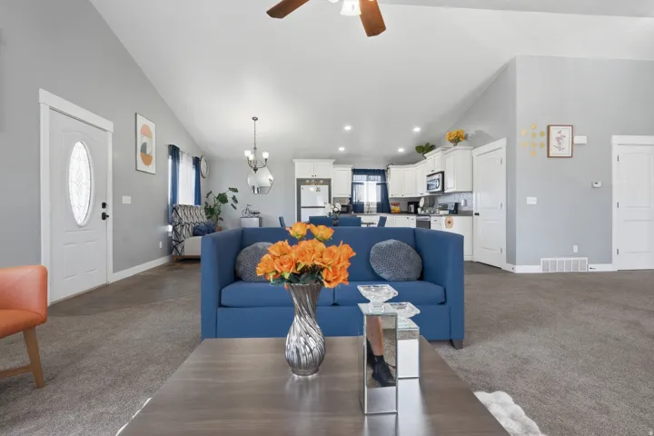 Vaulted ceilings with a ceiling fan, white paneled doors, and gray carpeting