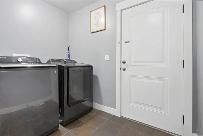 Laundry area with dark tile flooring and light gray wall paint
