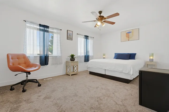 Spacious room featuring carpeted flooring, a ceiling fan, and two windows
