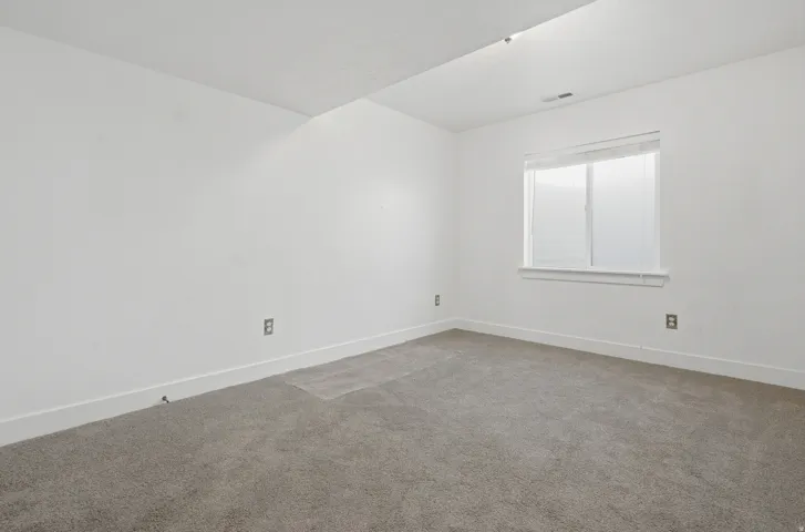 Neutral-toned carpeting, white walls, and a window with blinds