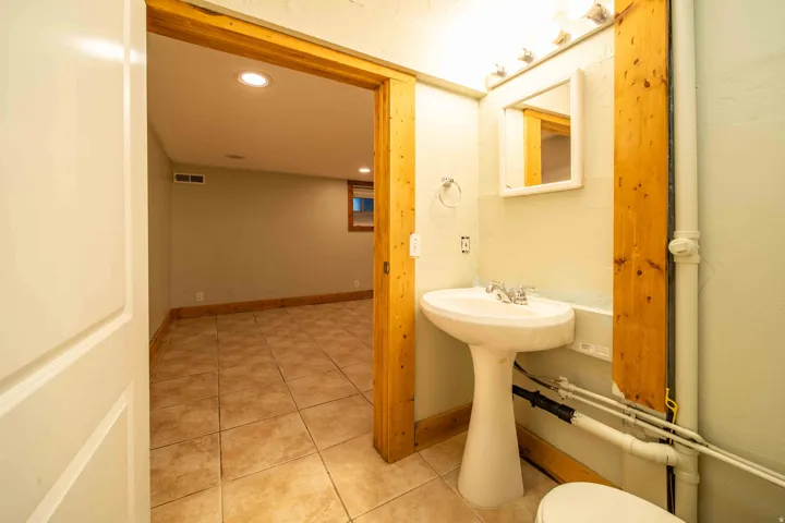 Pedestal sink with chrome faucet, framed vanity mirror, and tile flooring