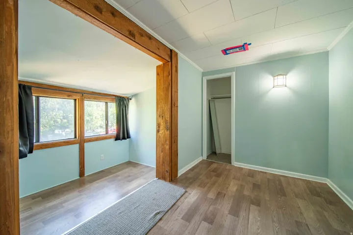 Wood-finish flooring, accent wall sconce, drop ceiling, and closet space