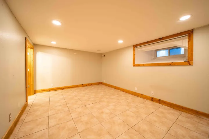 Recessed lighting, light-toned walls, tile flooring, wood trim, and a window