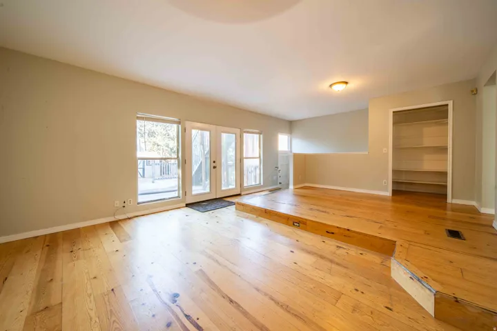 Light wood-finish flooring, built-in open shelving, and a raised floor section