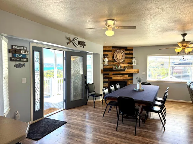 Wood-finish flooring, a fireplace with a wood-plank accent wall and mantle, and ceiling fans with integrated lighting