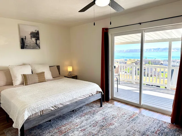 Hardwood-style flooring, ceiling fan with integrated lighting, sliding glass door, private deck, and scenic water with mountain backdrop