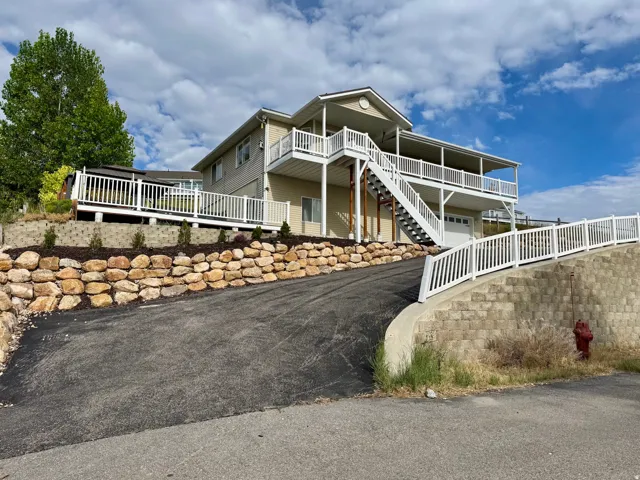 Multi-level exterior with ample covered deck space, white railing, and a stone retaining wall