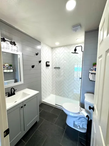 Modern bathroom featuring a walk-in shower with herringbone tile, a glass enclosure, and matte black fixtures