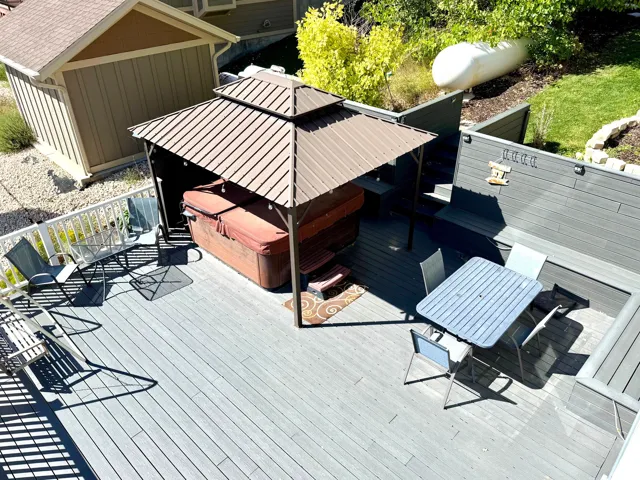 Spacious outdoor deck with composite decking, integrated built-in seating, privacy fencing, and a covered hot tub
