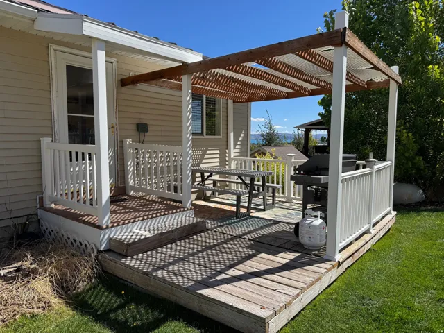 Multi-level deck with a wood pergola, white railing, and a slatted wood shade structure