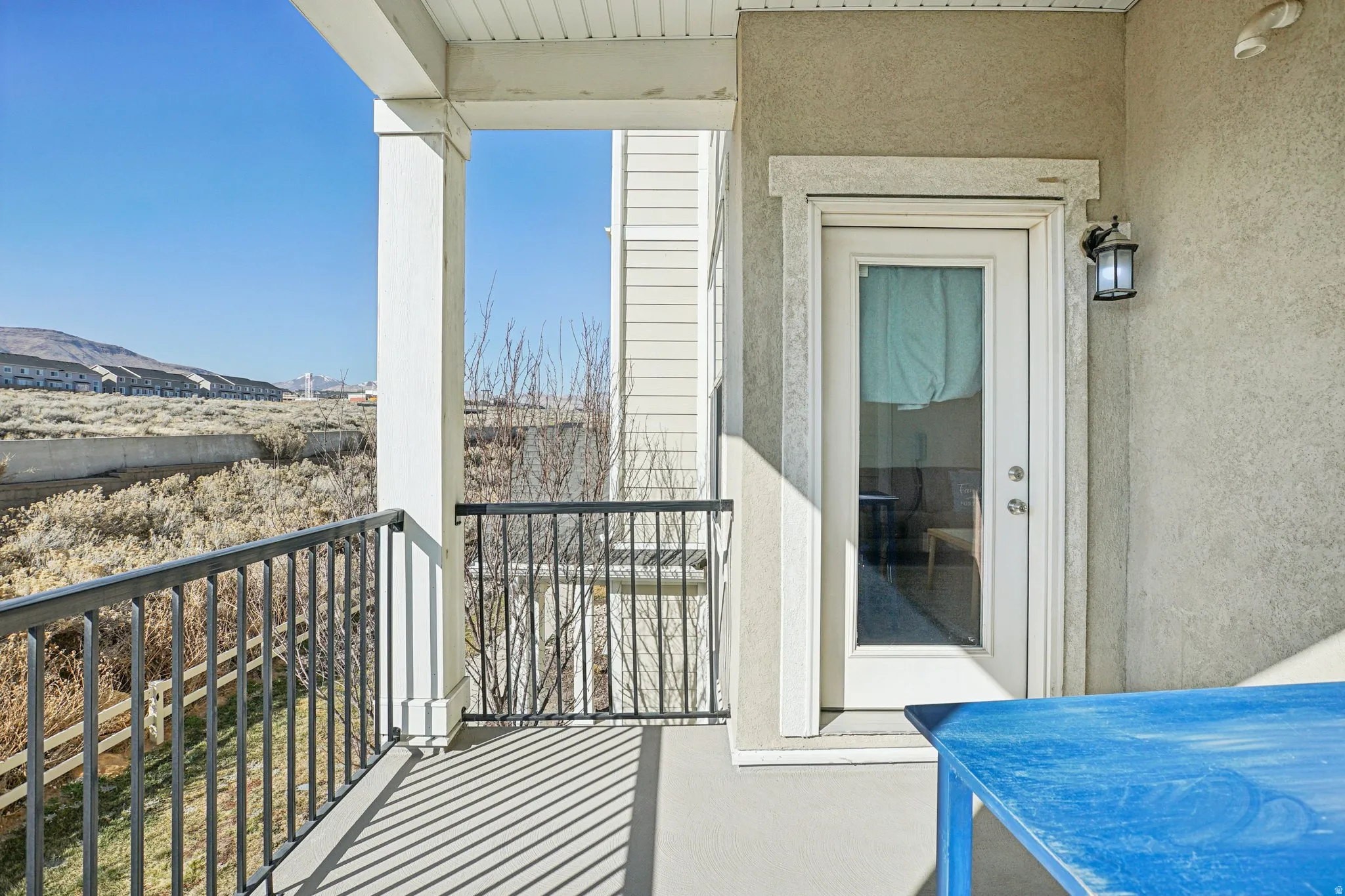 Private balcony with black metal railings, concrete flooring, and a full-light exterior door