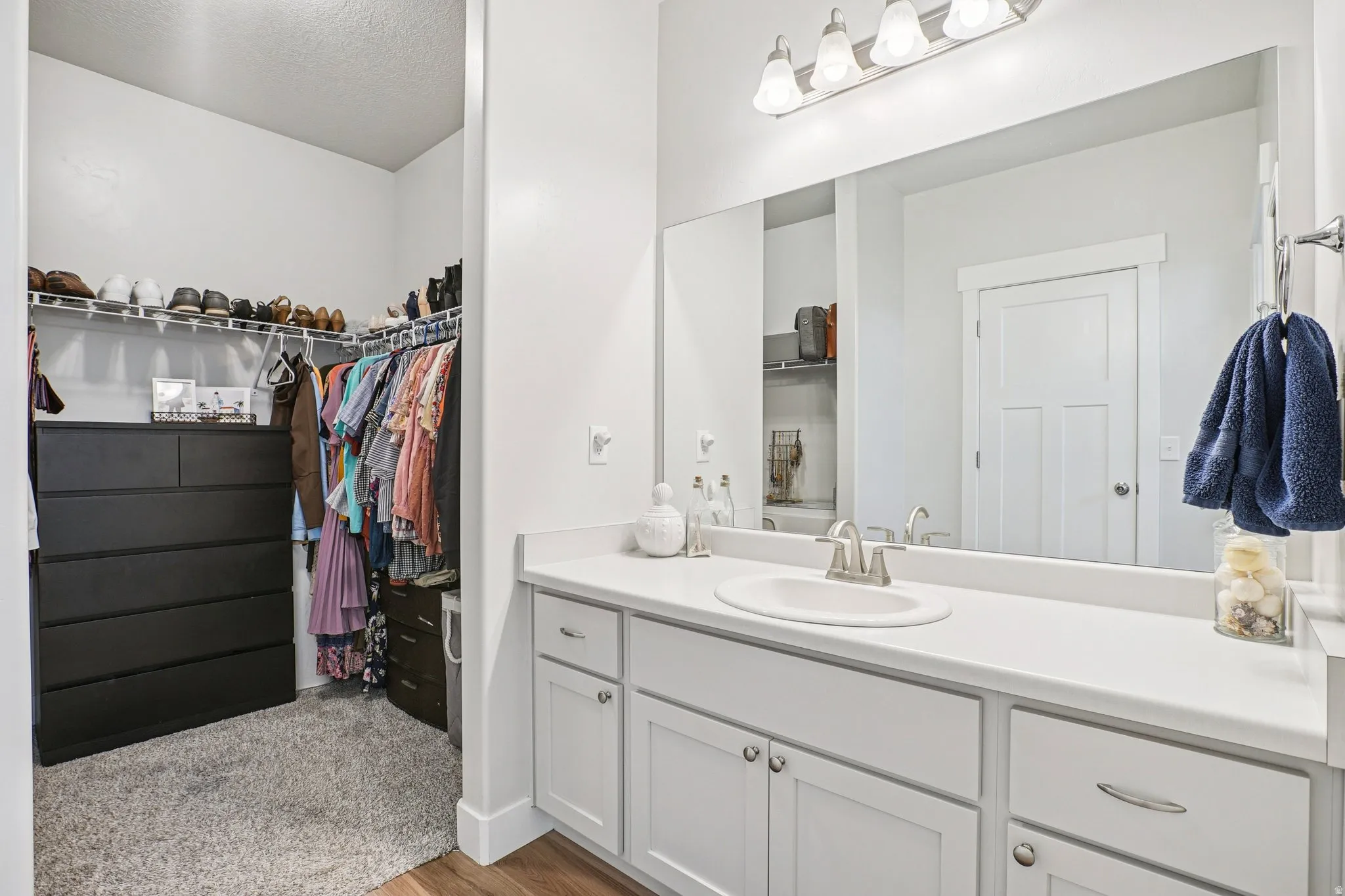 Bathroom vanity with an integrated sink and brushed nickel faucet, a large rectangular mirror, and white cabinetry