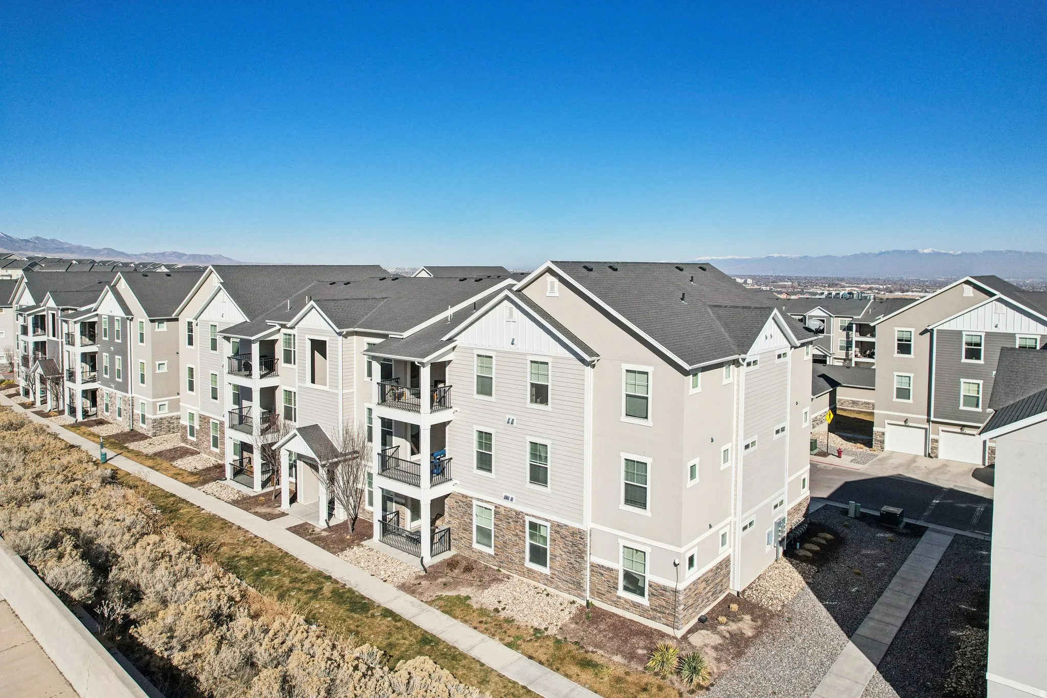Multi-story residential buildings featuring light-colored siding, dark shingle roofs, and stone accents