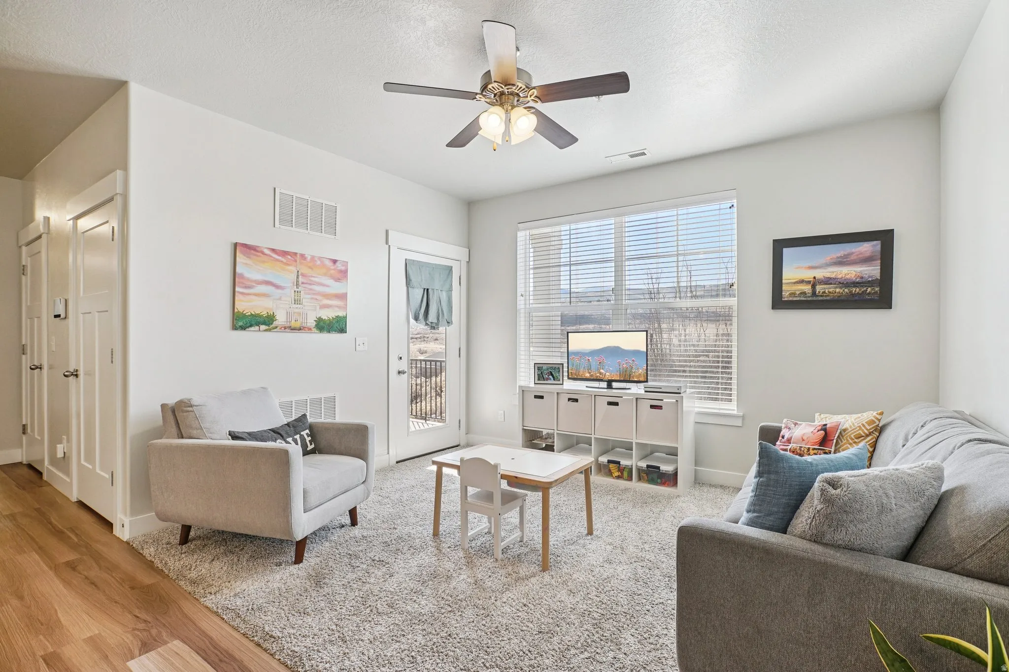 Laminate wood-finish flooring, white paneled interior doors, and a ceiling fan with integrated lighting
