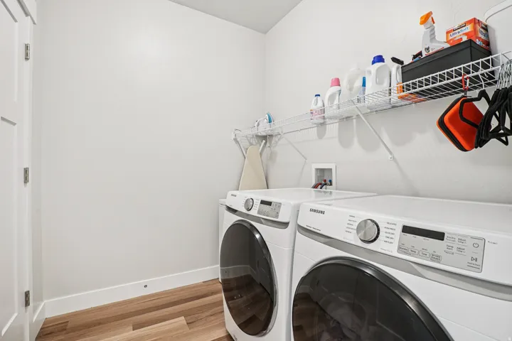Laundry area featuring a washer and dryer, wood-finish flooring, and wall-mounted shelving