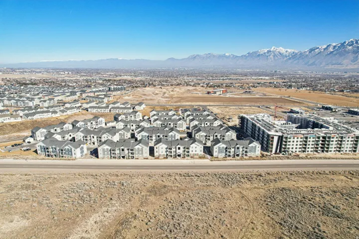 Expansive aerial perspective showcasing a residential development with multiple apartment complexes, several multi-story buildings, and a distant mountain range