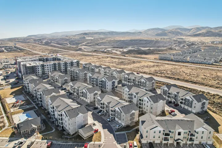 Expansive residential community featuring multi-story buildings with balconies, paved parking areas, and a visible playground