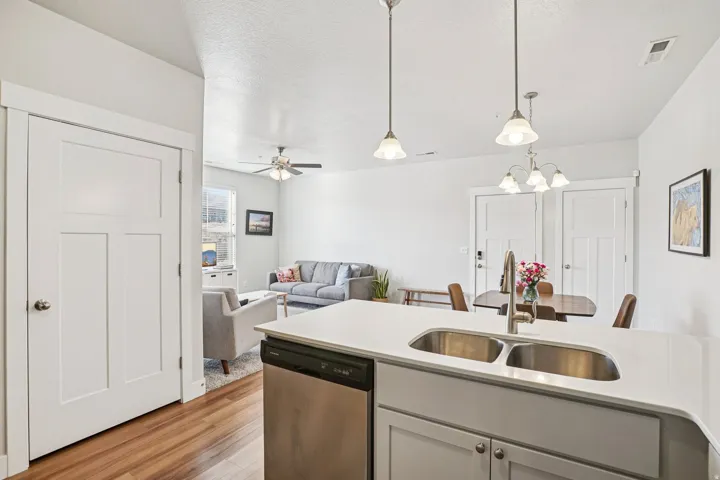 Kitchen island with a double stainless steel sink, pull-down faucet, and light-toned cabinetry