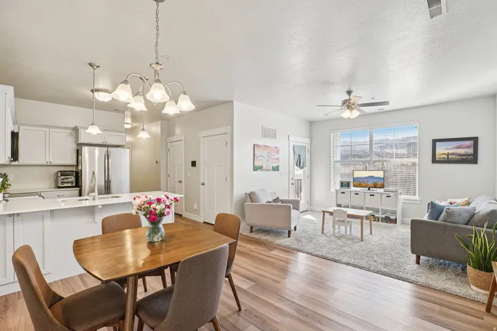 Spacious open-concept living area with wood-finish flooring, white cabinetry, a built-in kitchen island, and stainless steel appliances