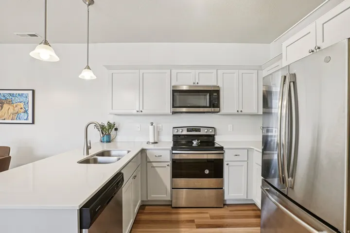 Kitchen featuring white cabinetry, stainless steel appliances, a double basin sink, and wood-finish flooring