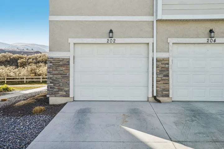 Single-car garage with overhead door, stone veneer detailing, and exterior wall lantern