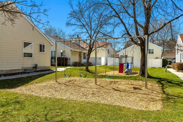 Grassed common area featuring swing sets and a children's play structure