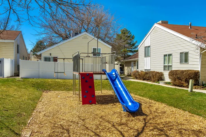 Outdoor recreation area featuring a play structure with a slide and climbing wall