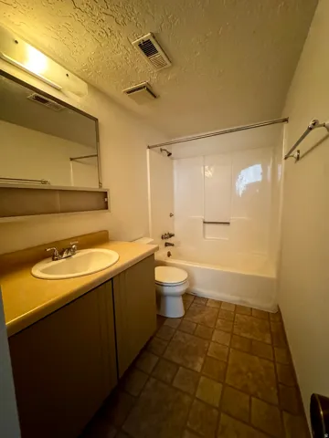 Bathroom featuring a vanity with an integrated sink, a built-in medicine cabinet, a full bathtub with a shower, and patterned flooring