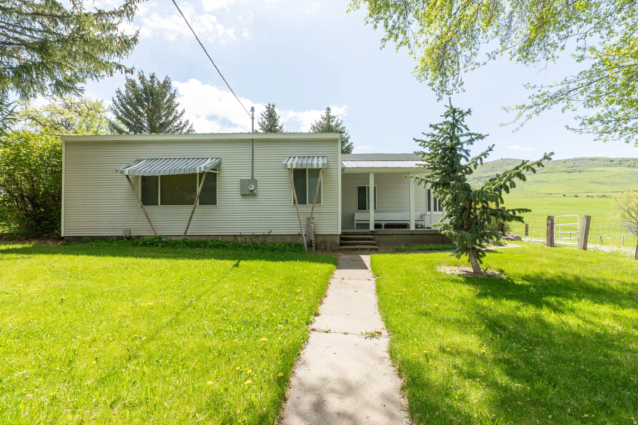 Single-story residence with white siding, covered front porch, and a metal roof