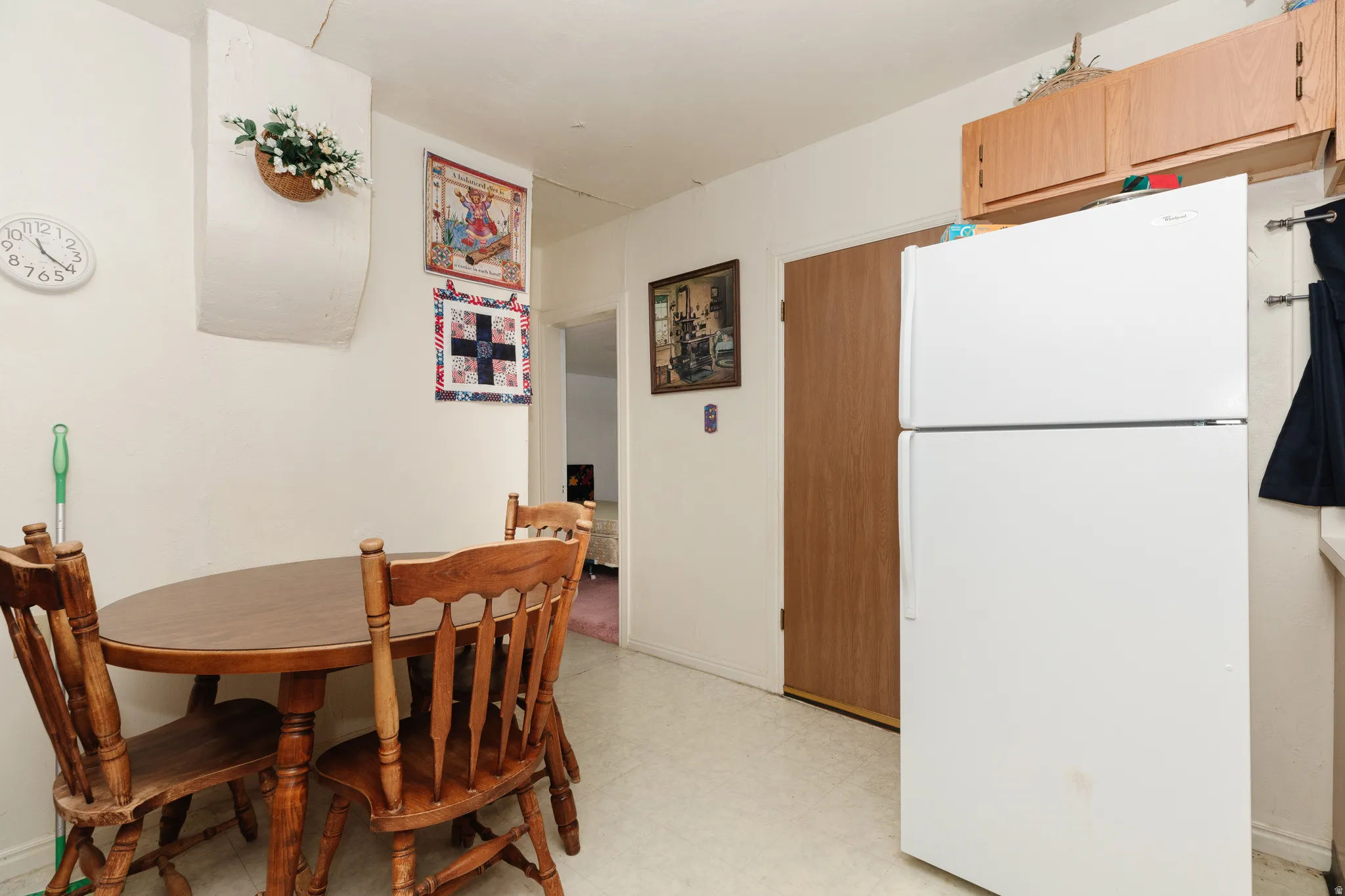 White walls, light-toned flooring, and a white refrigerator