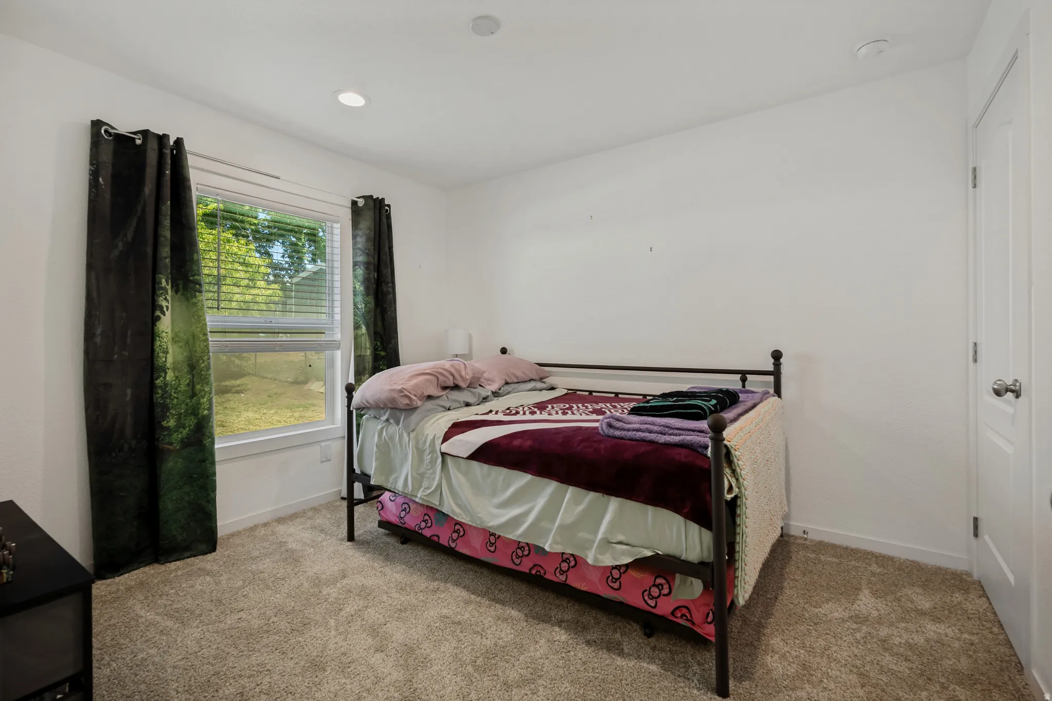Recessed ceiling lighting, white walls, carpeted flooring, and a single window with blinds