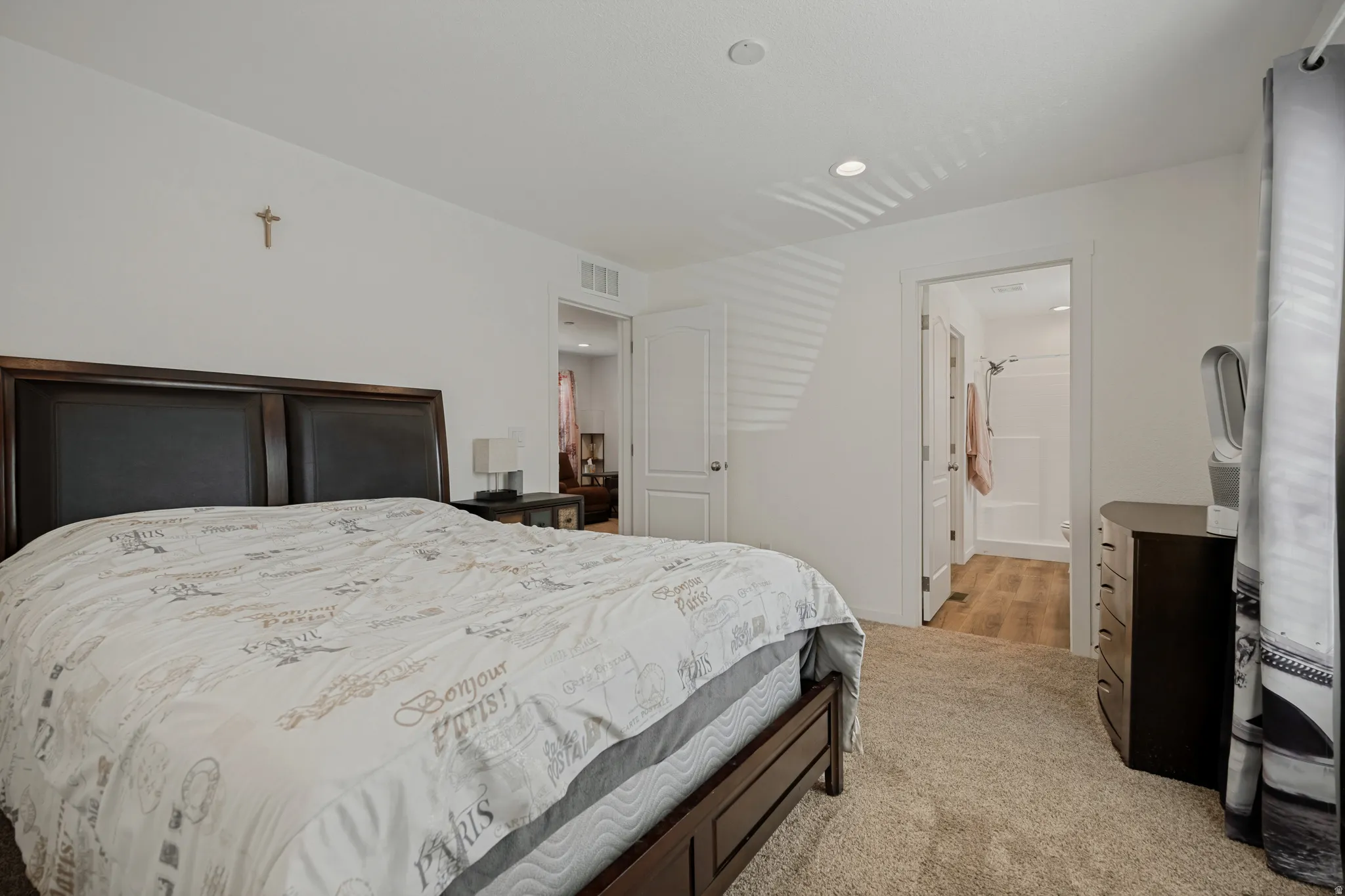 White walls, recessed ceiling lighting, light-toned carpet, and a wood-finish flooring in the adjacent space