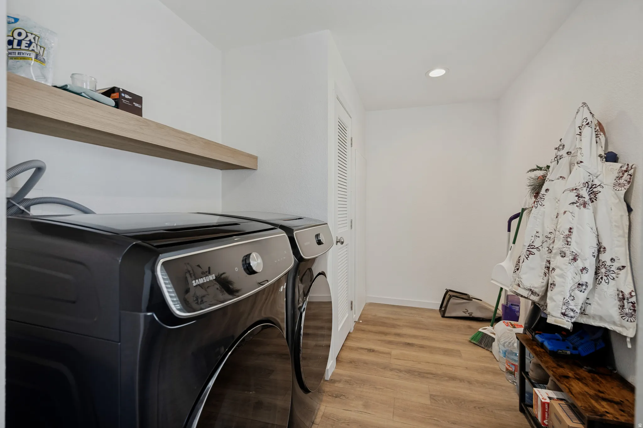 Recessed lighting illuminates the space, featuring a floating wood-finish shelf and wood-finish flooring